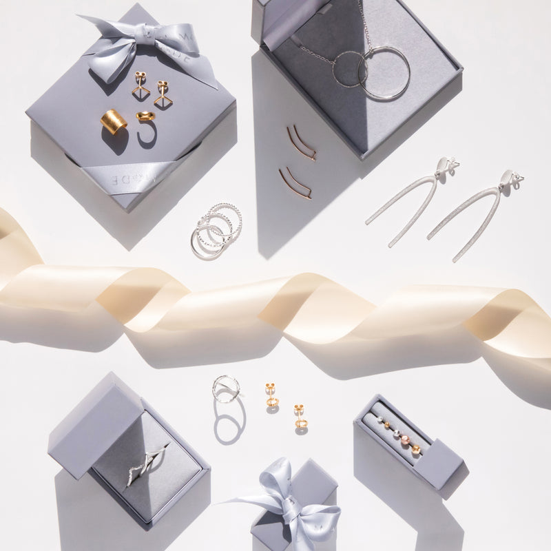 A variety of silver and gold jewellery displayed in gift boxes with ribbon